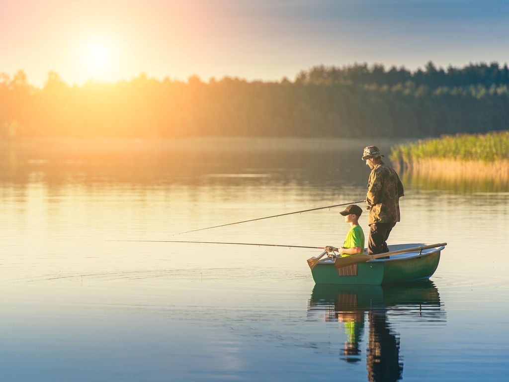 Father and son fishing on lake at sunset