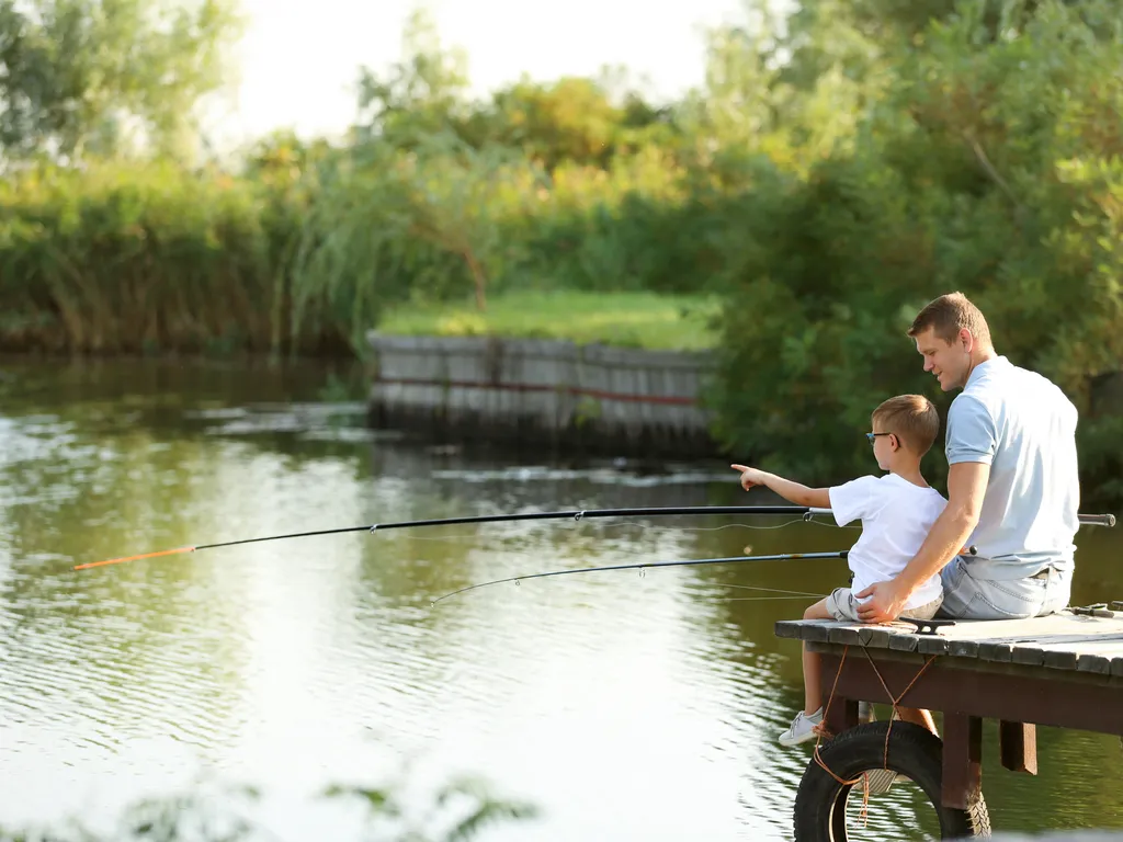 Dad and son fishing together on sunny day