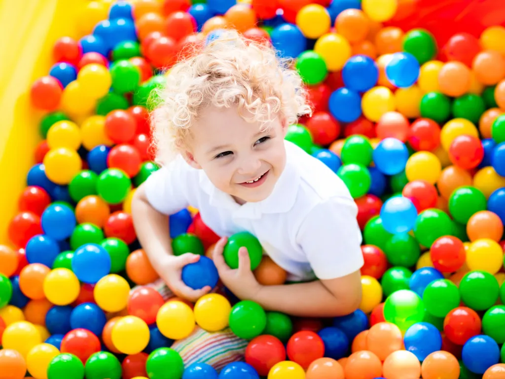 Happy laughing boy having fun in ball pit